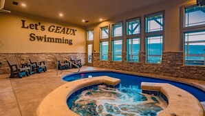 An indoor swimming pool with a hot tub, stone walls, and a view of the ocean. - Rockin' Ridge Retreat: Indoor Pool, Mtn Views, Home Theater, Games, Signature, near Attractions! (Sevierville)