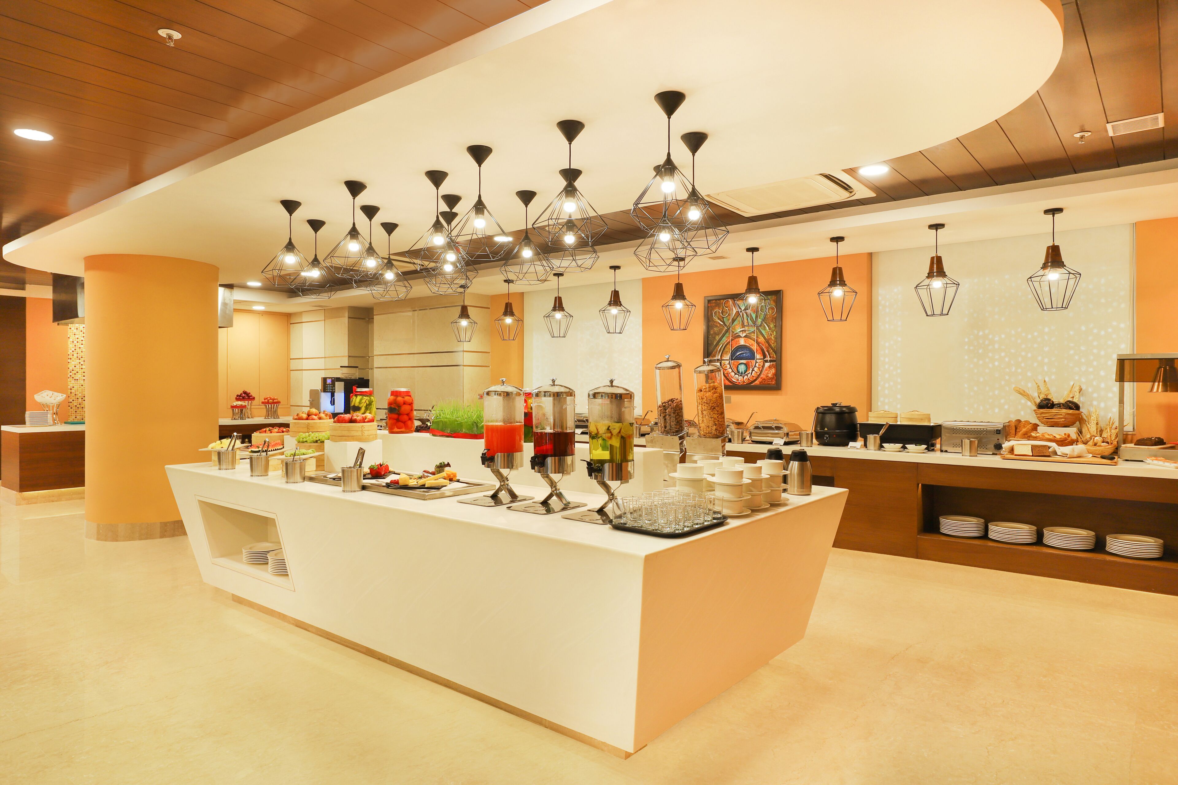 A modern breakfast bar with multiple drink dispensers, a coffee machine, and a variety of food items.