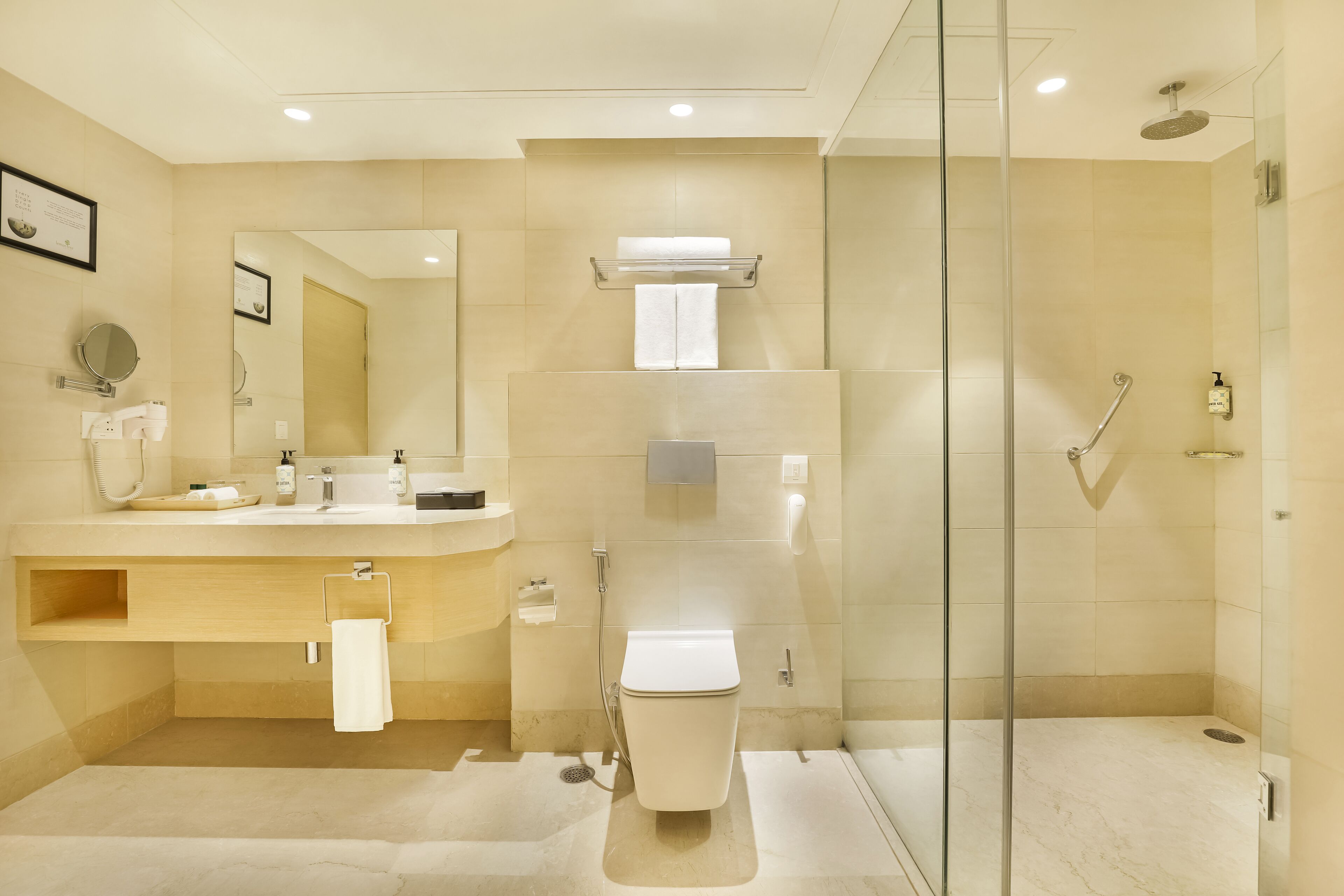 Un baño moderno con ducha de vidrio, inodoro, lavamanos con espejo y toallero.