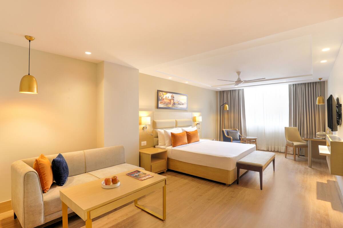 A hotel room with a bed, a sofa, a desk, and a chair.
