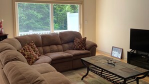 Ein Wohnzimmer mit einem Ecksofa, einem Couchtisch und einem Fernseher.