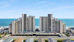 Hotel alto com átrio central, vários andares e vista para o oceano.
