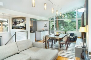 Eine moderne Küche mit hängenden Töpfen, ein Essbereich mit Tisch und Stühlen sowie eine Sitzecke mit Sofa.