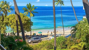 A beach with palm trees, a clear blue ocean, and a few people. - Summer Deal Beachfront 2BR Kona Condo Across from Magic Sands Beach (Kailua Kona)