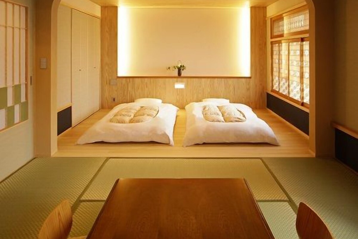 A traditional Japanese room with tatami flooring, a low wooden bed, and a sliding door.