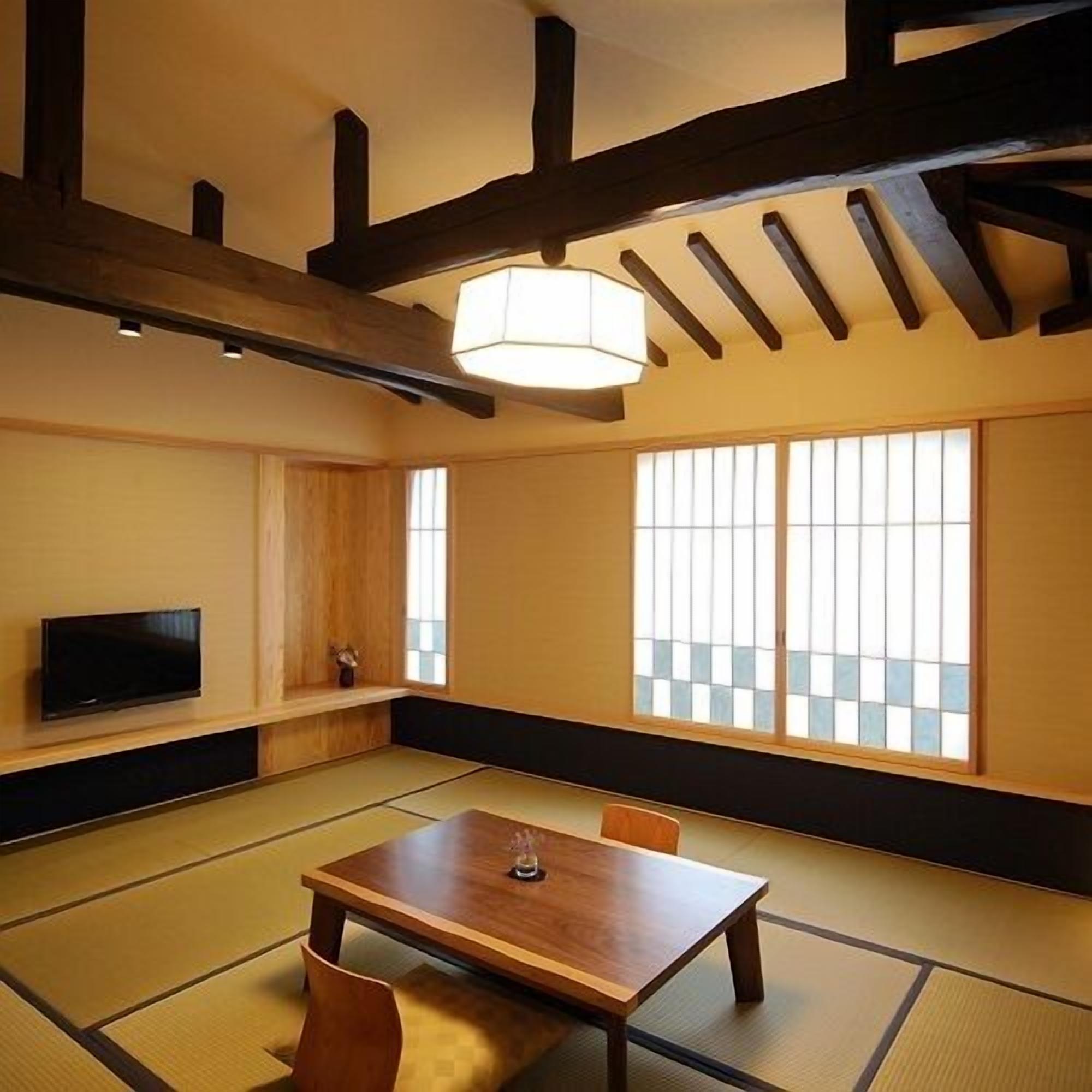 Una habitación japonesa tradicional con suelo de tatami, una mesa baja, un televisor y puertas correderas shoji.