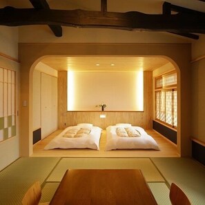 Una habitación tradicional japonesa con suelo de tatami, una cama baja de madera y una puerta corredera.