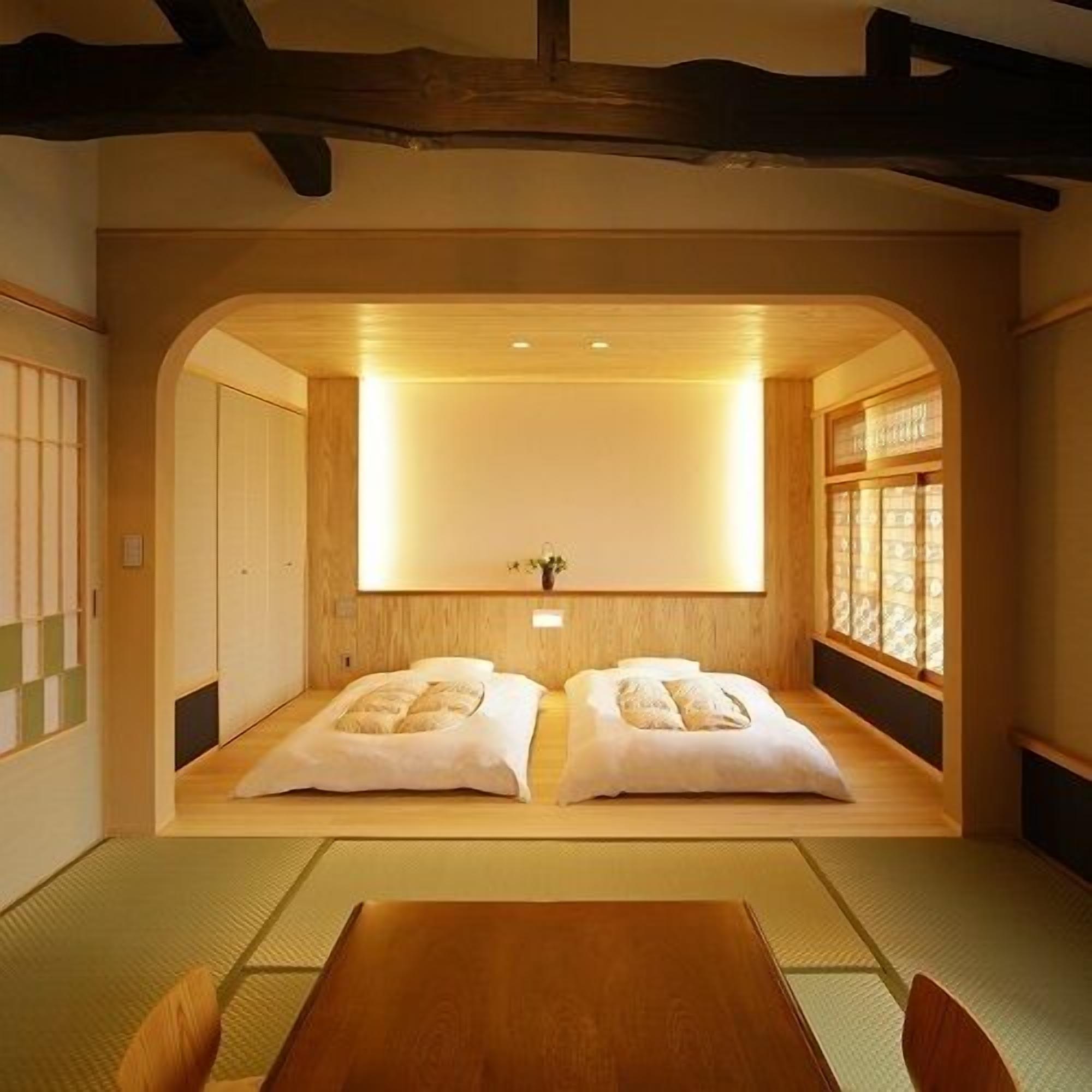 A traditional Japanese room with tatami flooring, a low wooden bed, and a sliding door.