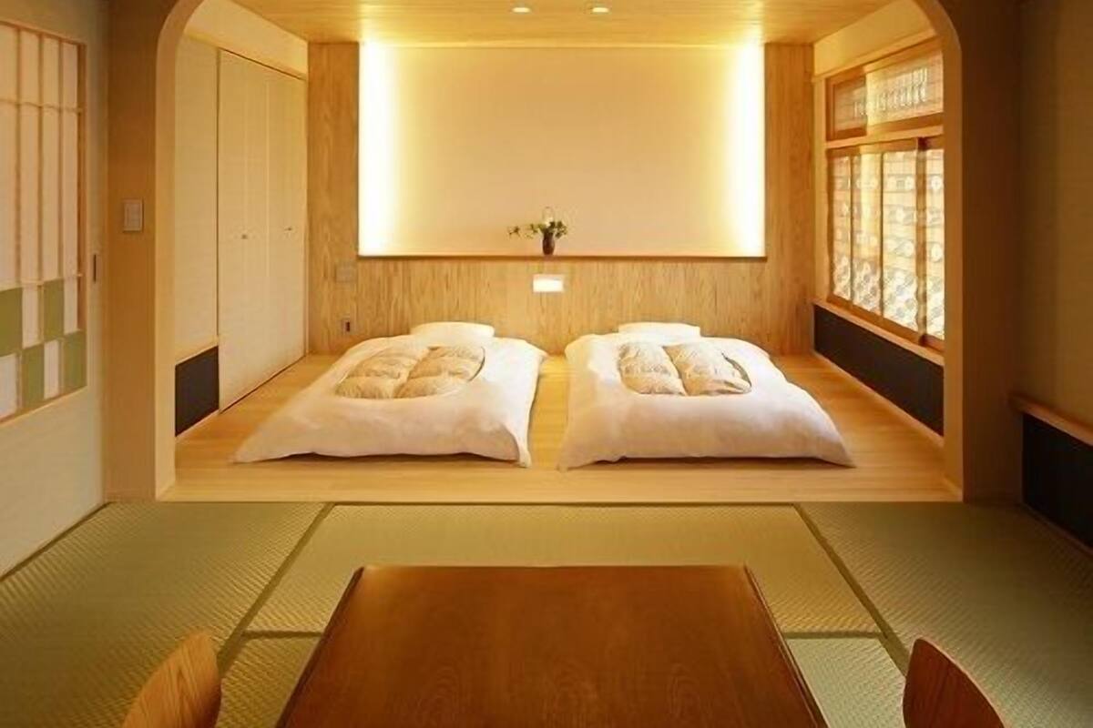A traditional Japanese room with tatami flooring, a low wooden bed, and a sliding door.