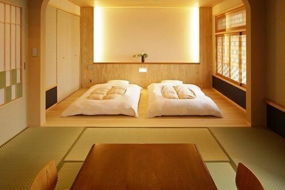 A traditional Japanese room with tatami flooring, a low wooden ceiling, and a sliding door.