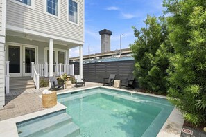 A residential property with a swimming pool, outdoor seating, and a view of a tall building in the background. - 7BR City Condo | Pool Access Near CBD (New Orleans)