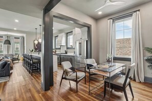 Une cuisine moderne dotée d’un grand réfrigérateur, d’un coin repas avec une table en verre et d’un salon avec un canapé et des fauteuils.