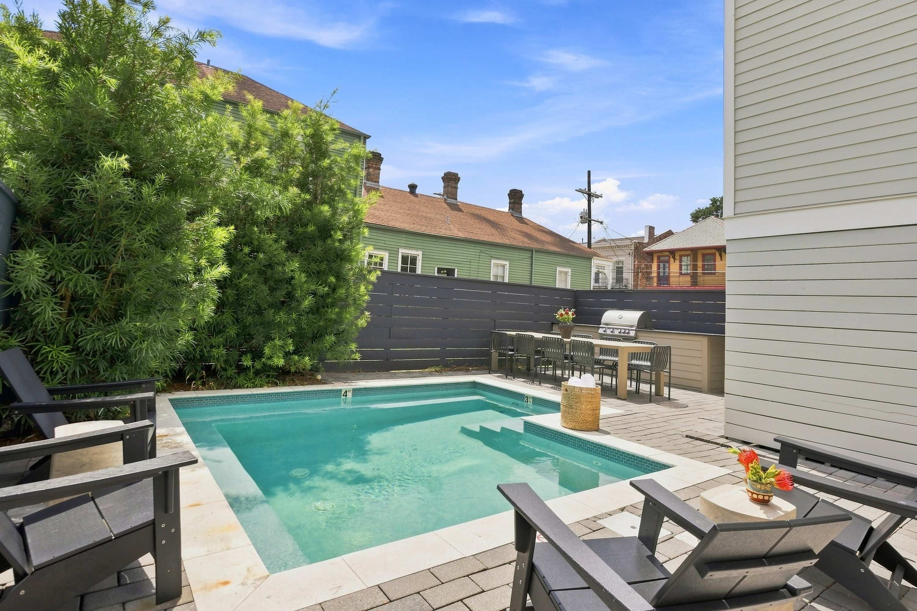 A swimming pool with a patio area, including lounge chairs and a barbecue grill.