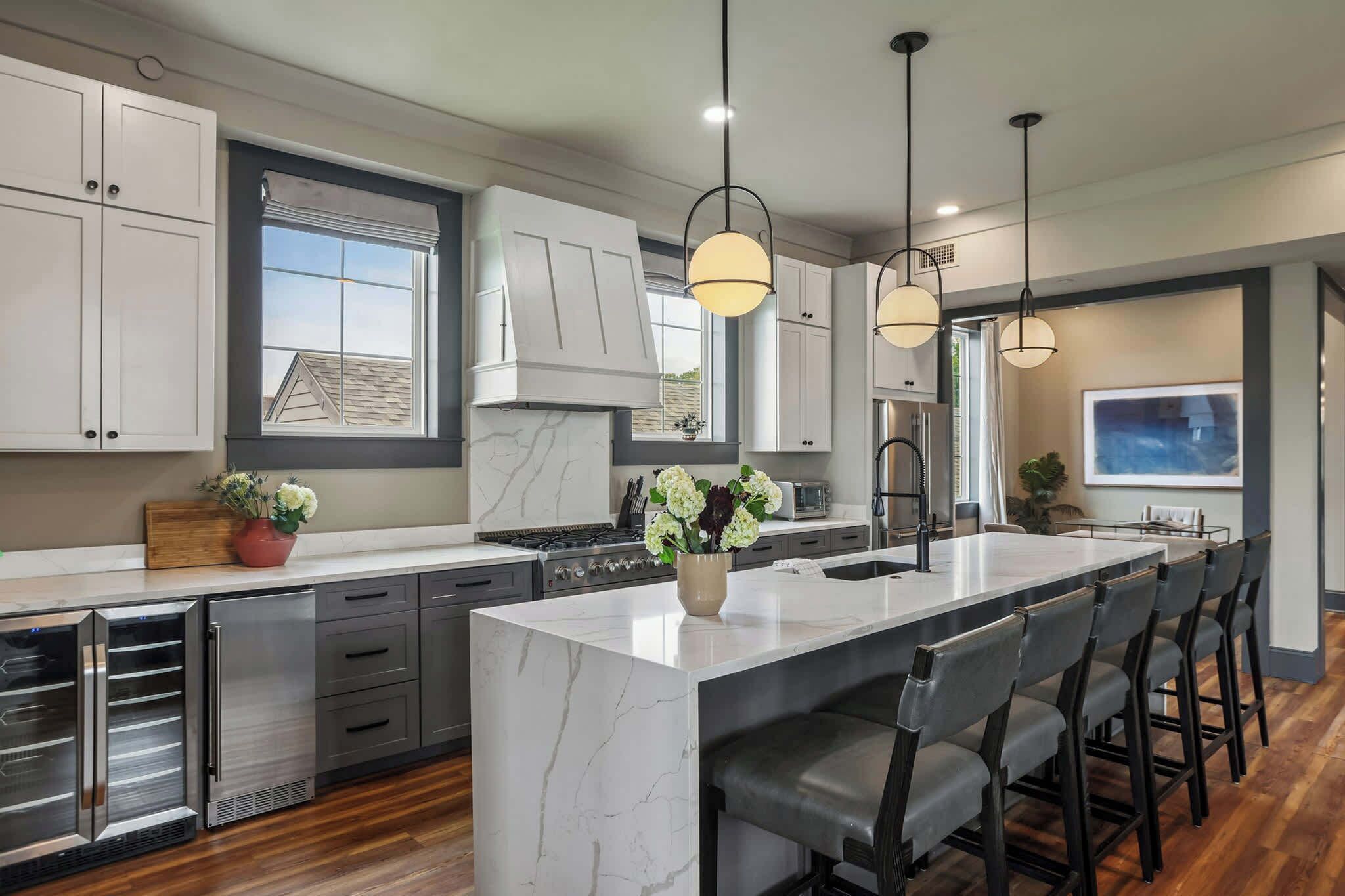 A modern kitchen with a large island, stainless steel appliances, and pendant lighting.