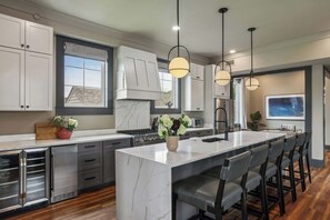 A modern kitchen with a large island, stainless steel appliances, and pendant lighting.