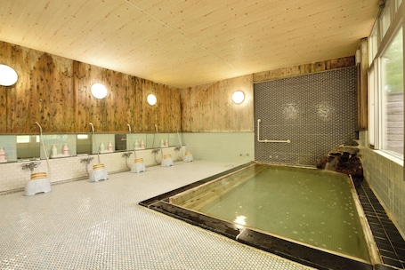 A wooden interior with a large bathtub, multiple sinks, and a tiled floor.