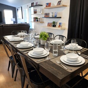 A dining area with a long table set for six, surrounded by chairs, with a potted plant on the table. - Red Rock Retreat (Page)