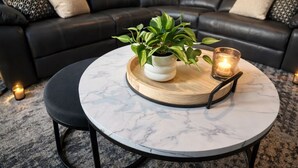 A modern living room with a black leather sofa, a round marble coffee table, and a potted plant. - Red Rock Retreat (Page)