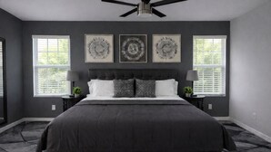 A bedroom with a large bed, dark walls, and three wall-mounted circular art pieces. - Red Rock Retreat (Page)