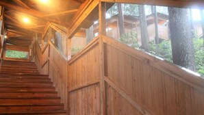 Una escalera de madera con barandilla que conduce a un espacio cubierto con ventanas.