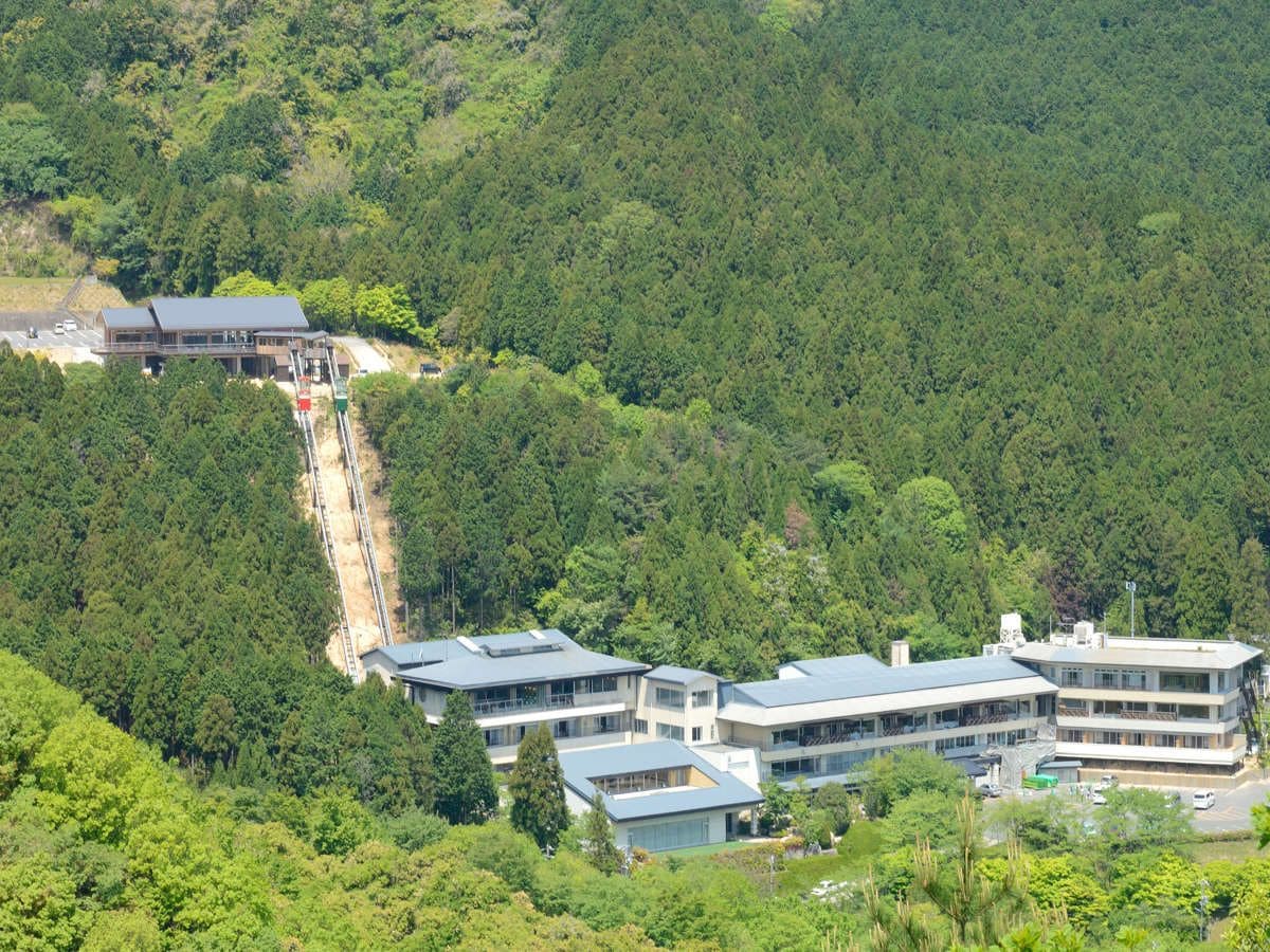 Un edificio de varios pisos con un diseño arquitectónico moderno, rodeado de un bosque denso.