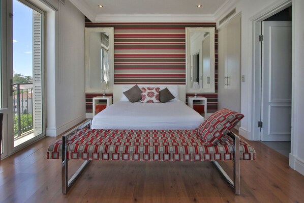 Une chambre à coucher moderne avec un grand lit, un banc et un mur à rayures.