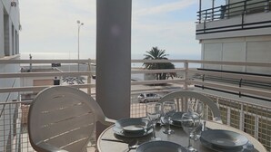Eettafel gedekt met borden, glazen en bestek op een balkon met uitzicht op een stadsgezicht.