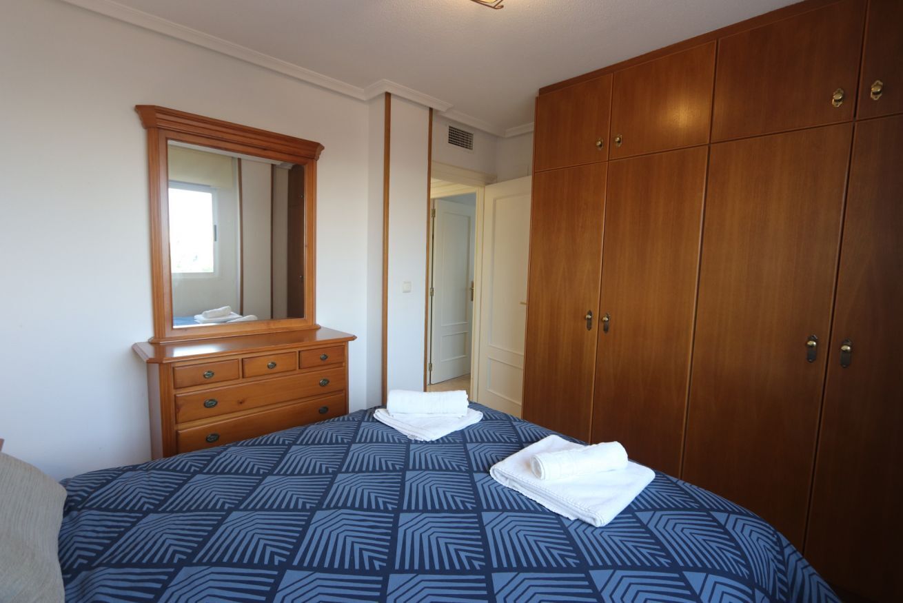 Un dormitorio con una cama grande, un armario de madera y un espejo sobre el tocador.