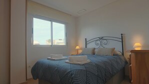 Een slaapkamer met een bed, twee bedlampen, een raam en een nachtkastje.