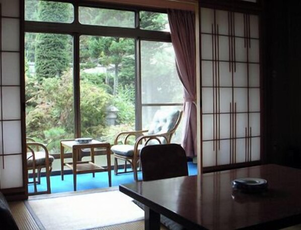 A room with tatami flooring, a low table, and a view of a garden through large windows. - Bessho Onsen Saito Ryokan (Ueda)