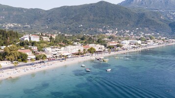 Una località costiera con spiaggia, imbarcazioni e edifici lungo il lungomare.