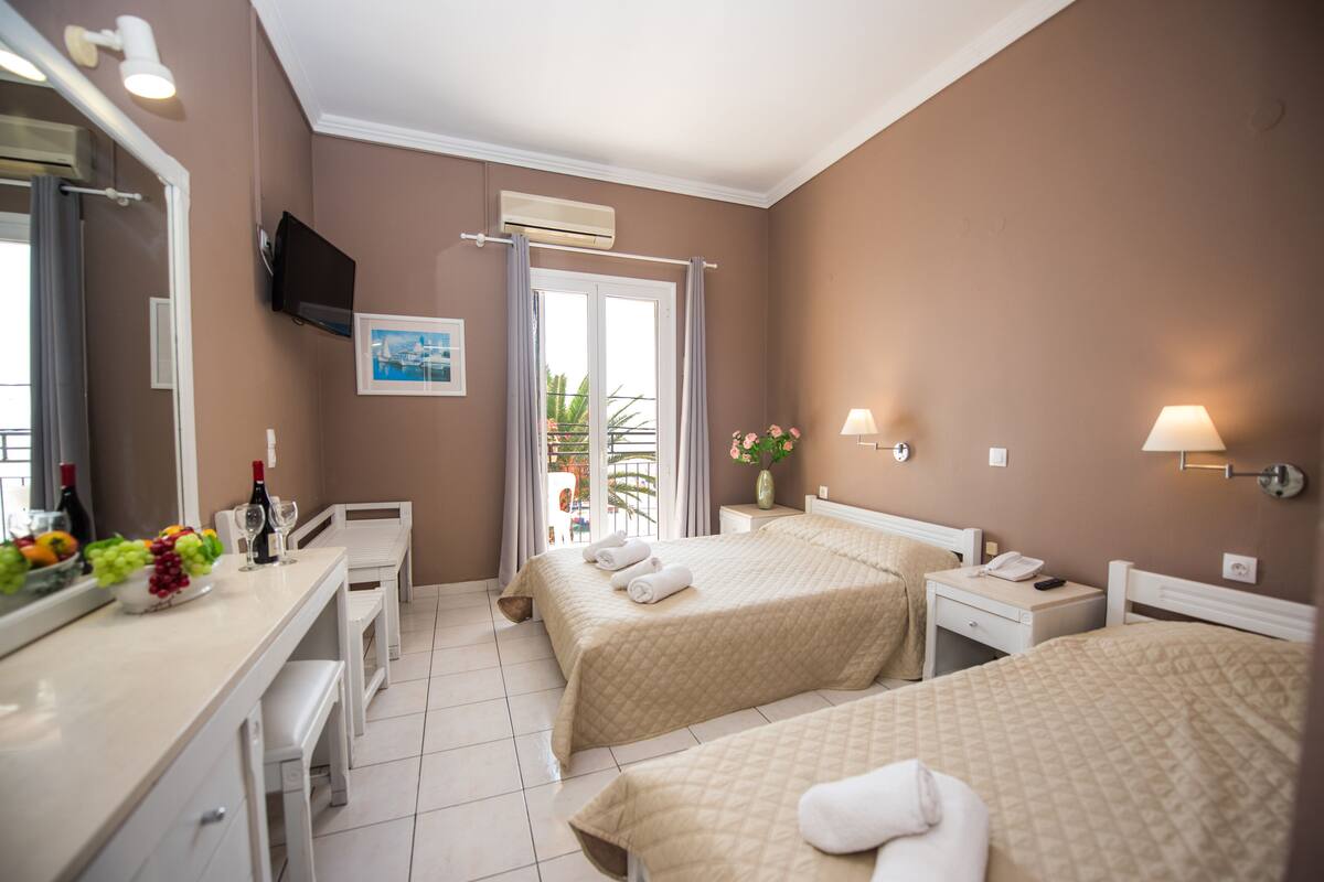 A hotel room with two beds, a desk, a chair, a TV, and a window with curtains.
