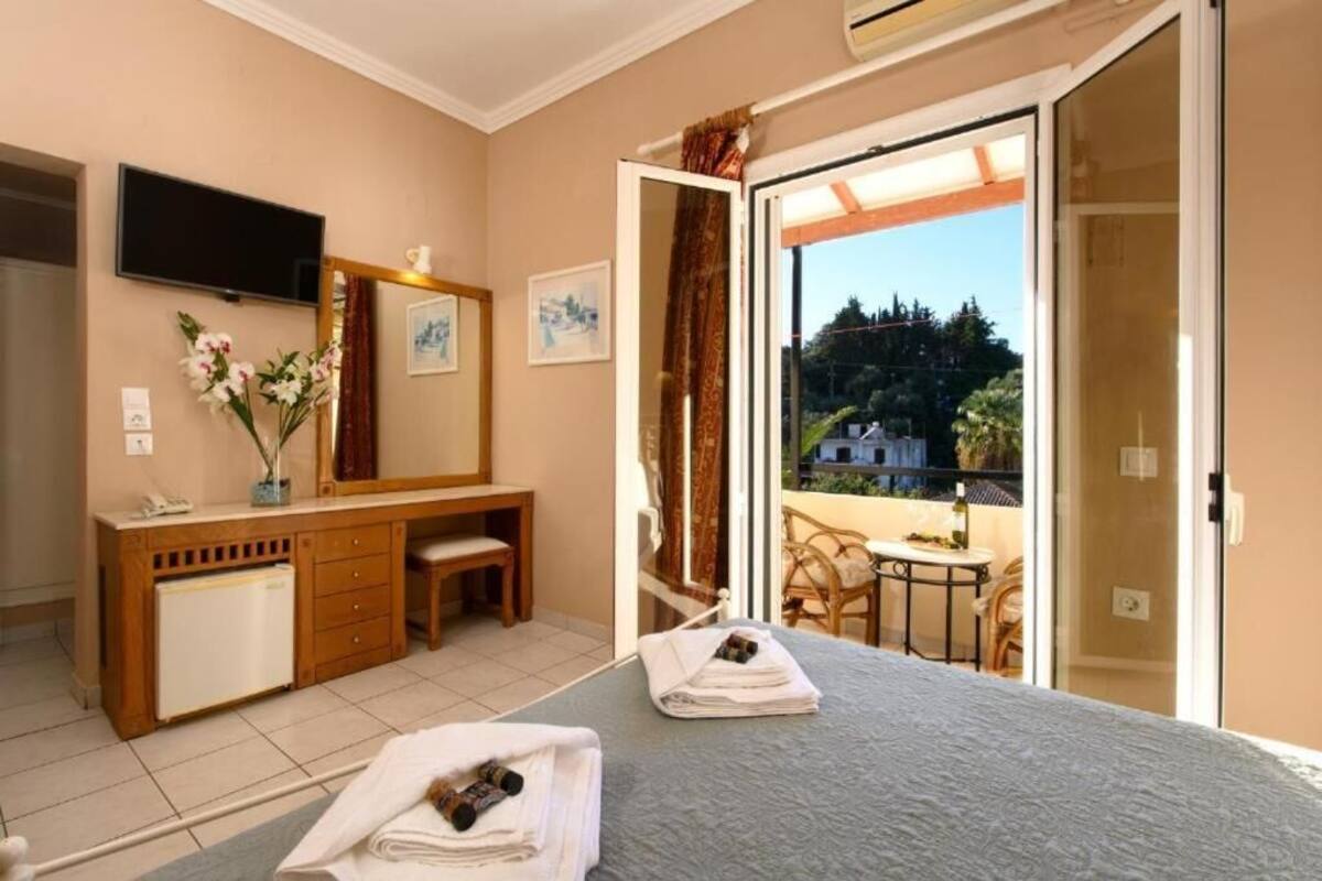 A hotel room with a bed, a desk, a chair, a TV, and a balcony with a view.