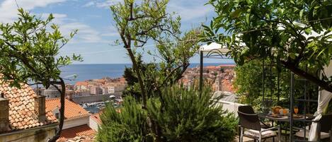 Una terrassa amb taula i cadires, amb vista a un paisatge urbà costaner.