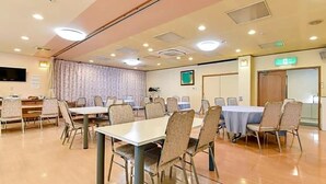 Une salle de conférence équipée de tables et de chaises, d’un téléviseur et d’une porte portant un panneau indiquant la sortie de secours.