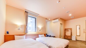 Une chambre d’hôtel avec deux lits, une fenêtre avec des rideaux, un climatiseur fixé au mur et un miroir.