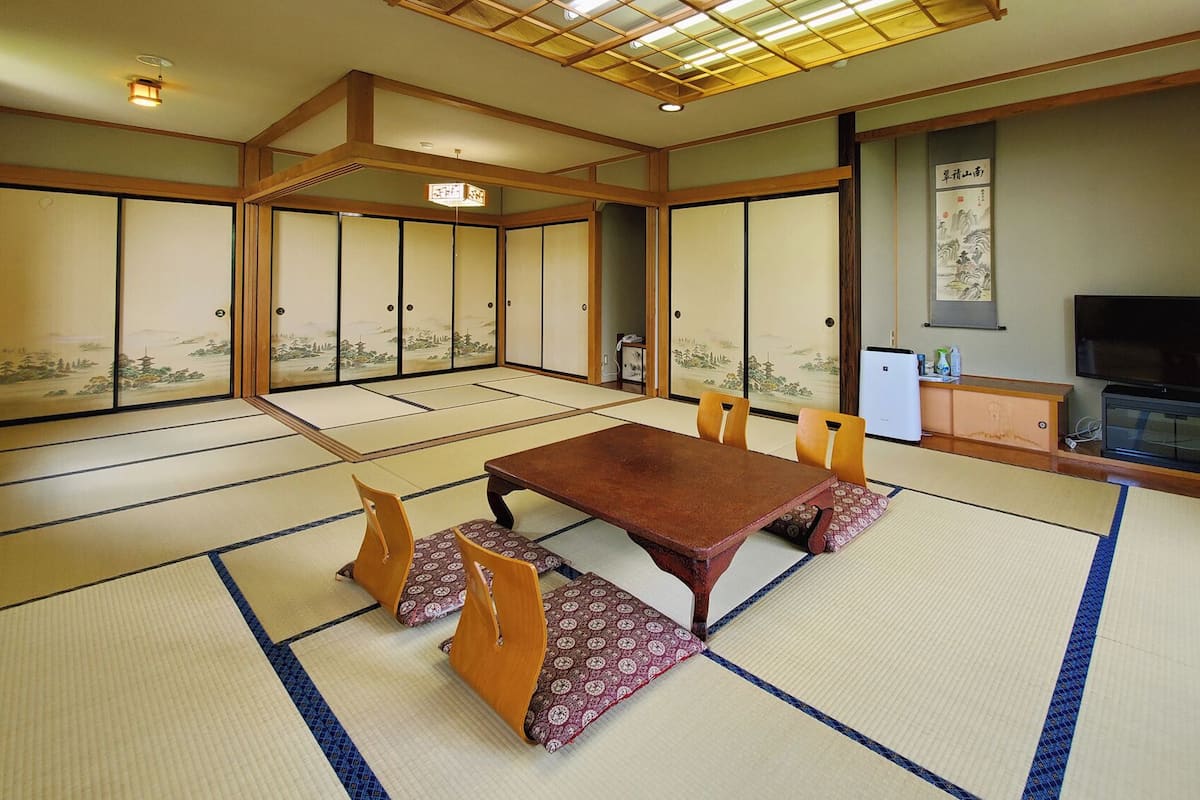 Une pièce de style japonais traditionnel, avec un sol recouvert de tatamis, une table basse et des portes coulissantes décorées de motifs artistiques.