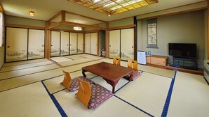 A traditional Japanese room with tatami flooring, a low table, and sliding doors with artwork. - Shikanoyu Tsuchiya (Tsumagoi)