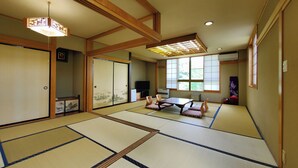 A traditional Japanese room with tatami flooring, a low table with cushions, sliding doors, and a ceiling fan. - Shikanoyu Tsuchiya (Tsumagoi)