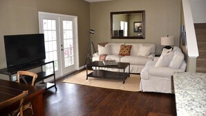A living room with a sofa, coffee table, TV, and a lamp. - Lucaya 4 Bedrooms 3 Baths Townhome in Gated Community (Kissimmee)