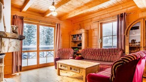 Interior acogedor de una cabaña de madera con un sofá a rayas, una mesa de centro de madera y una estantería.