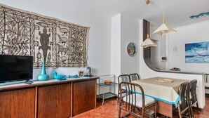 Un comedor con una mesa, sillas y un televisor sobre un mueble de madera.