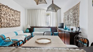 Una habitación con sofá, una mesa de comedor y dos lámparas colgantes.