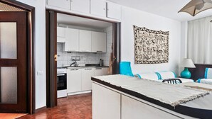 Una cocina moderna con armarios blancos, salpicadero de mármol y una silla azul.
