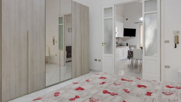 A modern interior with a large mirror, a patterned carpet, and a view into a kitchen area. - Dimora del Delfino Curioso (Lecce)