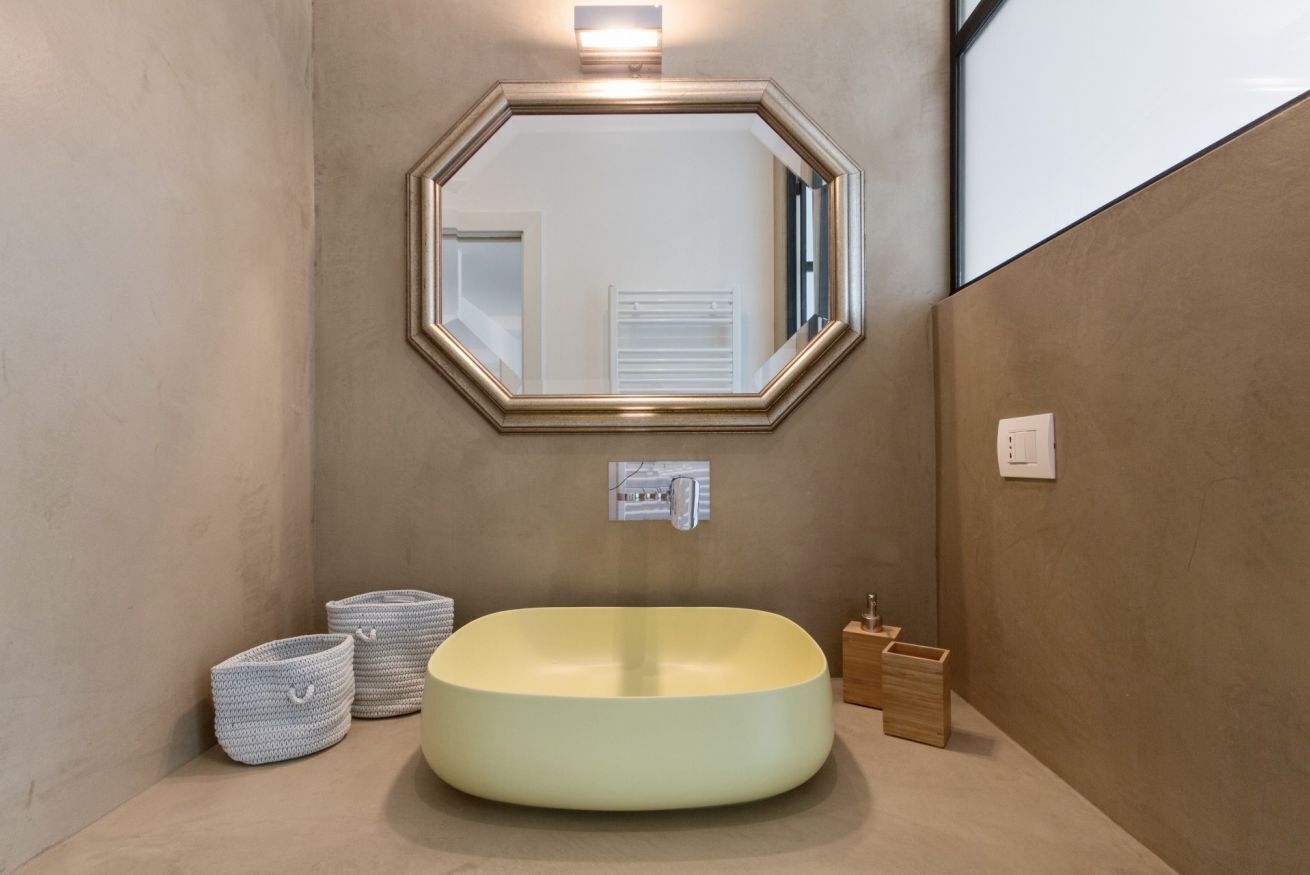 Une salle de bain avec un lavabo rond, un grand miroir et un porte-serviettes.