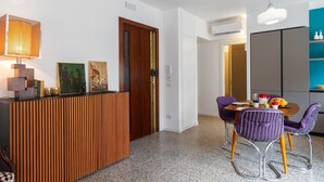 A modern kitchen with a wooden island, a dining area with purple chairs, and a pendant light. - Inner City Apartments (Lecce)