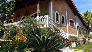 A large brick building with a red roof, white columns, and a white fence. - Country house in Atibaia for rent with swimming pool with solar heating and Wi-Fi. (Atibaia)