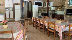 A dining area with a long table, chairs, and a small side table with a plant. - Country house in Atibaia for rent with swimming pool with solar heating and Wi-Fi. (Atibaia)