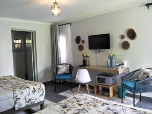 A modern hotel room with a bed, a desk, a television, and a seating area. - Kwetu Home ~ Sagana -A Modern Farm Stay -Sleeps 1- 18 (Kirinyaga County)